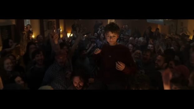 Spike is lifted into the air by his fellow townspeople in celebration. (28 Years Later)