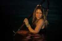 Zephyr is in the water with a spear, preparing for a shark attack