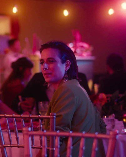 A woman looks over her shoulder under pink lights at a wedding reception