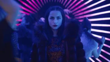 Eve is standing in a neon hallway surrounded by people