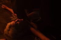 A cloaked figure is holding a knife to the neck of a woman lying on the floor (Hell Motel)