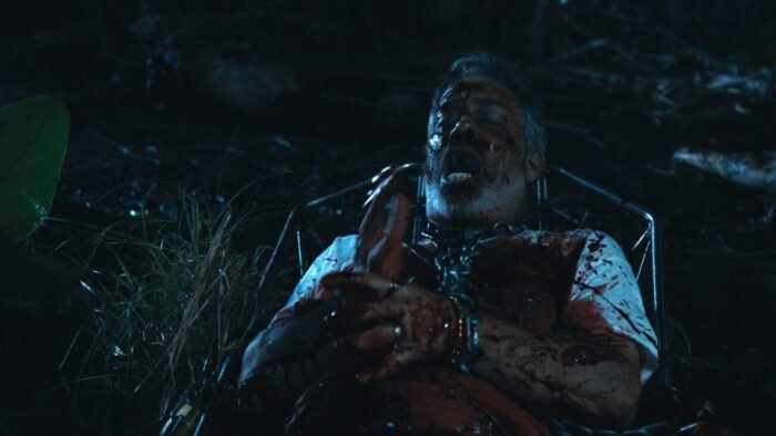 A man covered in blood holds a hand in the swampland (GATOR LAKE)