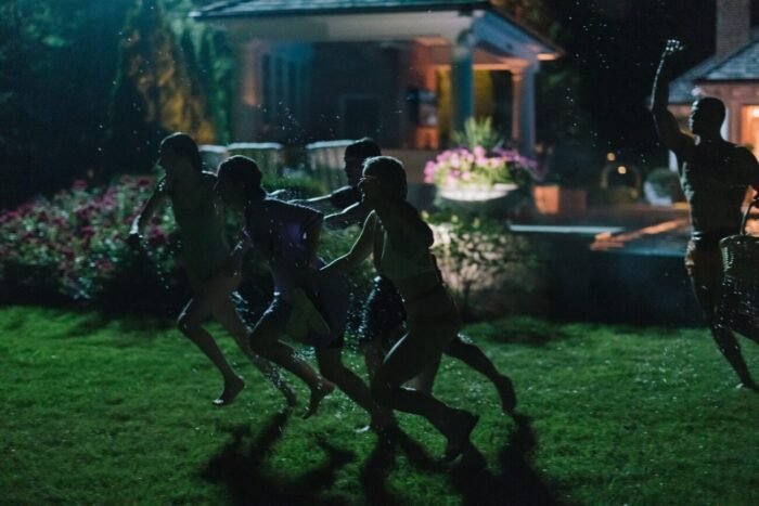 the silhouetts of several people can be made out running away from a house in the dark of night.