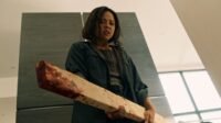 A woman holding a bloody 2x4 in front of a refrigerator (PINS AND NEEDLES)