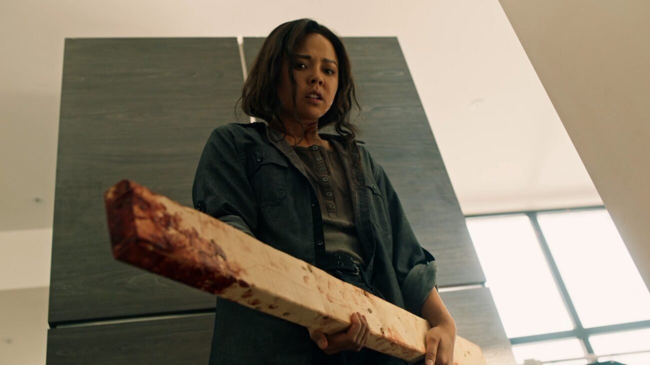 A woman holding a bloody 2x4 in front of a refrigerator (PINS AND NEEDLES)