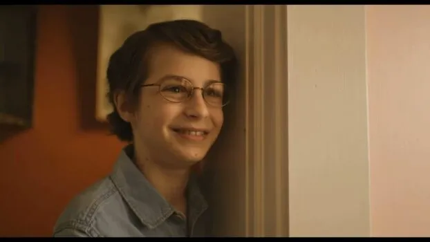 Young Chuck stands next to a doorway and smiles