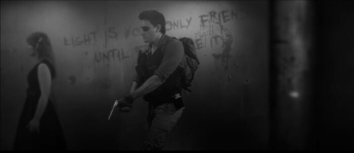 A woman and man walk through a hallway with writing on the wall. (THE WAVES OF MADNESS)