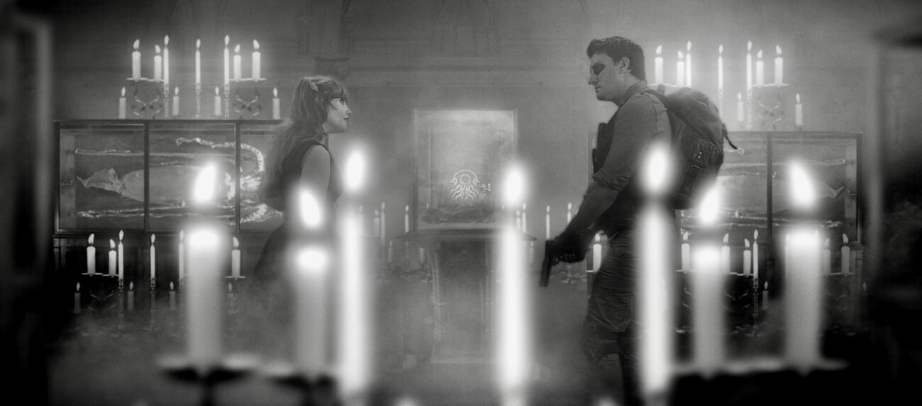A woman and a man are seen talking in a room with artifacts and lots of candles (WAVES OF MADNESS)