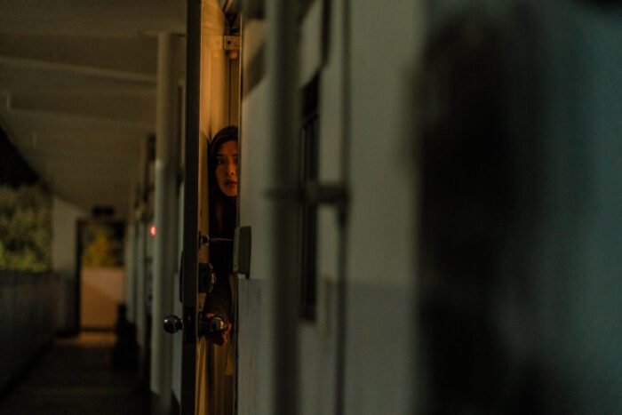 A woman peeks out of her door.