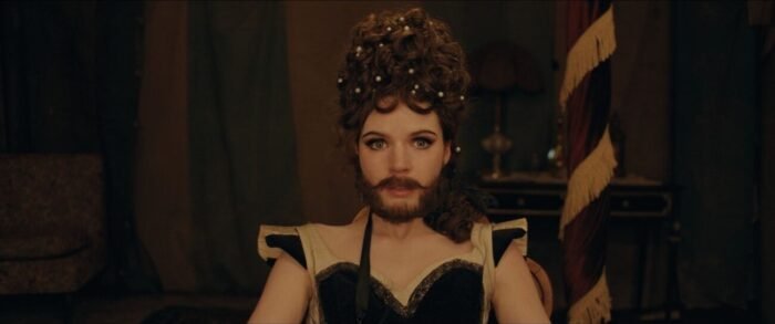 A bearded woman looks directly into the camera. (The Bearded Girl)