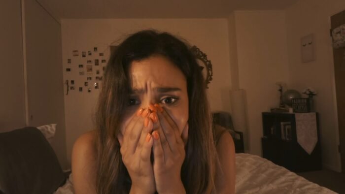 a woman holds her hands over her face and mouth. (Don't Log Off)