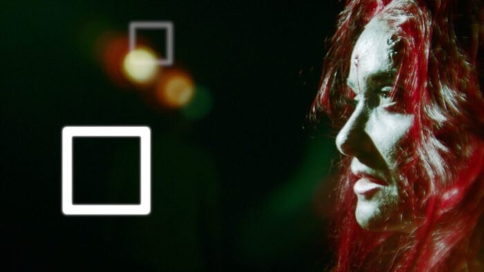 A disheveled looking woman lit by a spotlight.