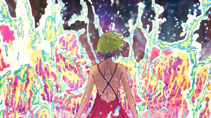 A woman stands in the ocean with her back to the camera and a colorful burst of water springs up in front of her (Gill)