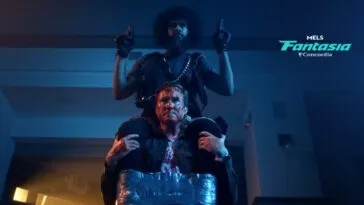 A man sits atop another mans shoulders. He is holding guns in each hand and duct taped to the man he is on top of. (Hold the Fort)