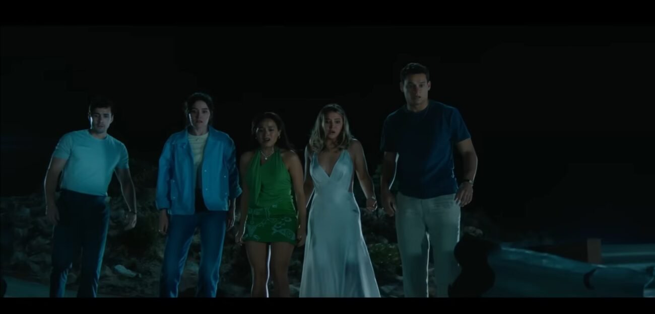 The five main friends, looking over the cliff at the wrecked car