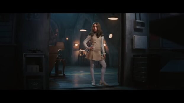 M3GAN stands in a doorway, hands on hip.