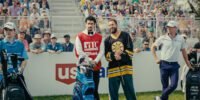 Happy Gilmore and his caddy talk while fans surrounding them look on.