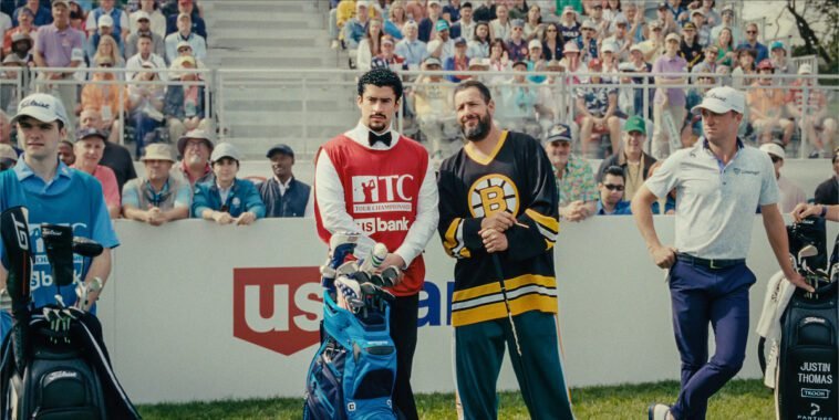 Happy Gilmore and his caddy talk while fans surrounding them look on.
