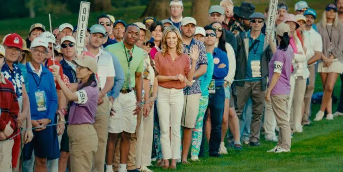 Victoria stands in the center of a crowd roped off from the golf course green.