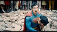 A man helps Superman out of a huge hole of rubble concrete