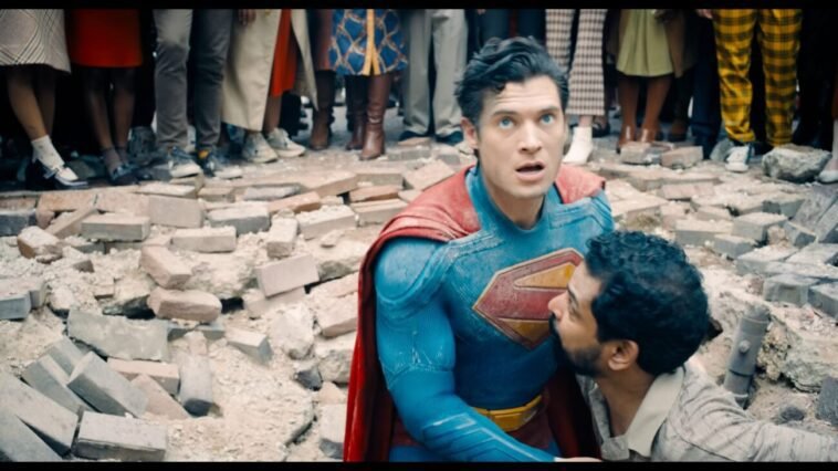 A man helps Superman out of a huge hole of rubble concrete