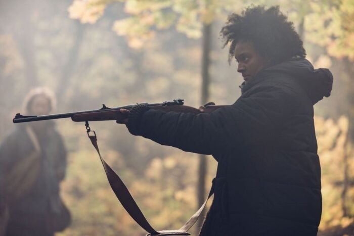 A woman holding a rifle in the woods (The Well