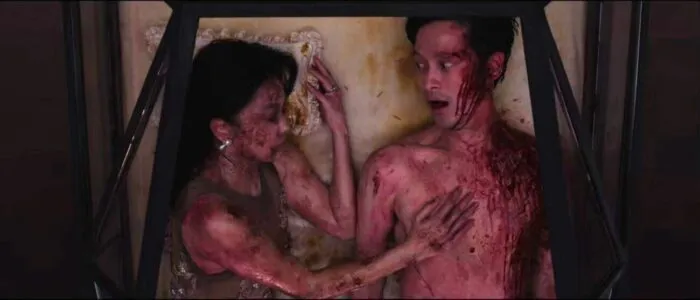 A man lays beside a woman covered in maggots (Tomb Watcher)