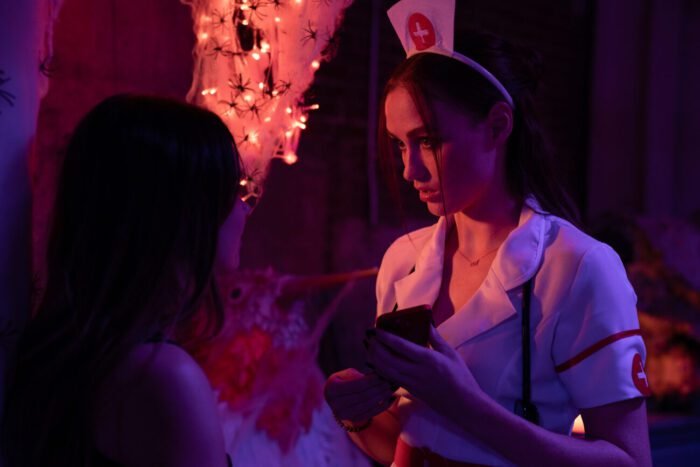 a young woman in a nurse's outfit is seen talking to someone.