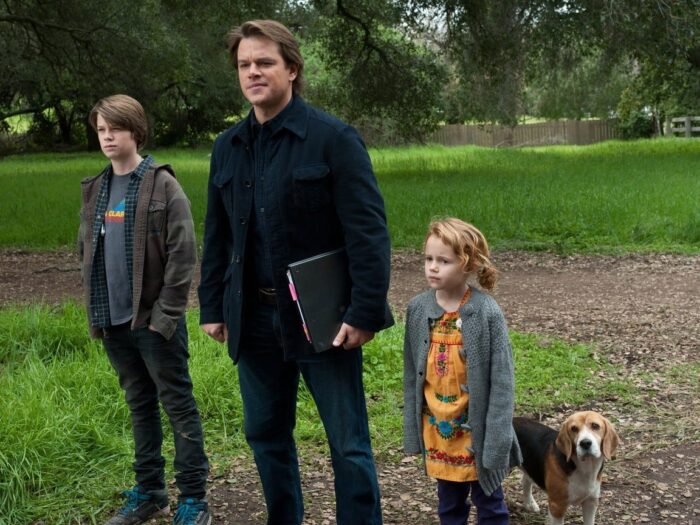 A father with his dog and his two kids watch a display in the film We Bought a Zoo.