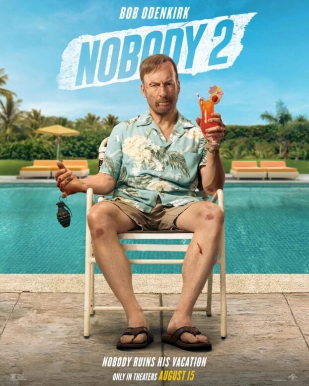 Hutch sits in a beach chair with one hand holding a grenade by a finger and the other holding a drink.