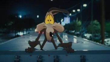 Wile E. Coyote gives a worried look while crouched on top of a moving semi truck in the film, “Coyote vs. Acme” (2026).