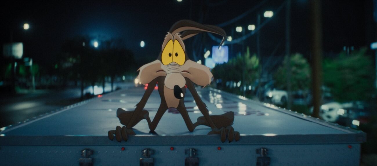 Wile E. Coyote gives a worried look while crouched on top of a moving semi truck in the film, “Coyote vs. Acme” (2026).