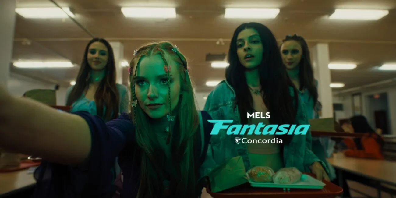 A young woman with braids and butterfly clips outstretches her arm past the camera while three other girls stand behind her, one holding a lunch tray.