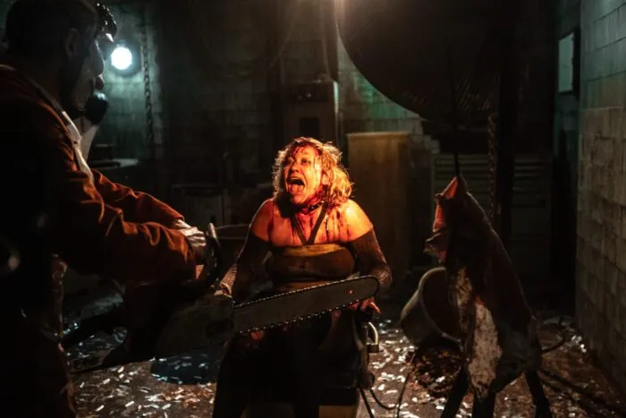 A woman is seen tied up and screaming in a chair as a man approached her with a chainsaw.