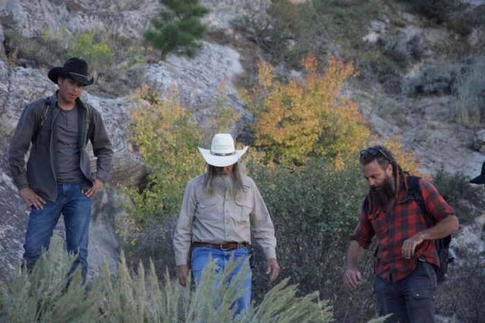 Josh Feldman, Charlie Snider, and Chad Ollinger peer down into a mine and discuss the best way to explore it.