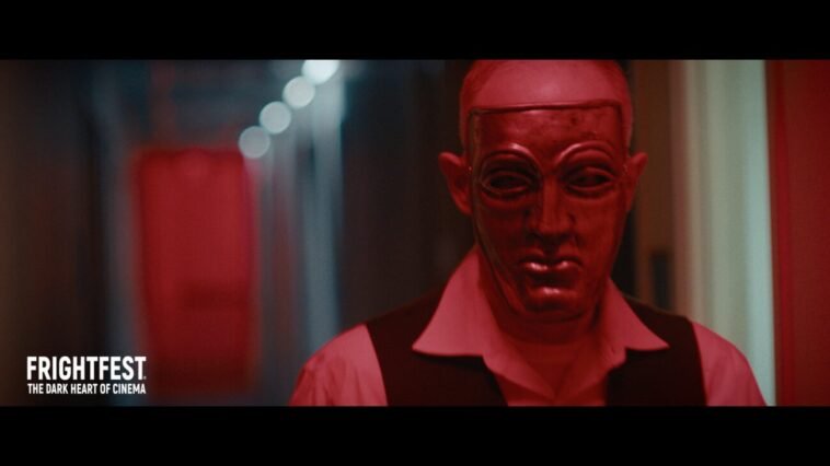 A man wearing a mask walks down a long hallway (Night of Violence)