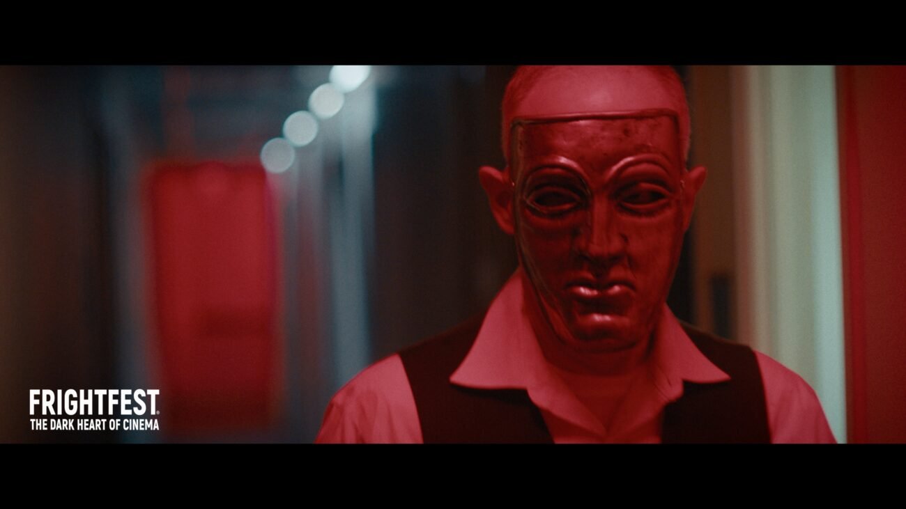 A man wearing a mask walks down a long hallway (Night of Violence)