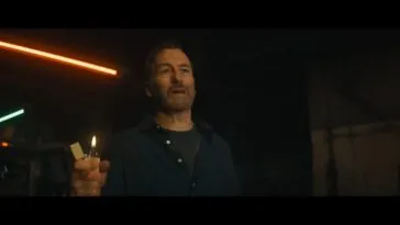 Hutch (Bob Odenkirk) stands with a lighter in his hand.