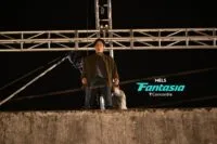 A stunt performer at the edge of a building rigged to a crossbeam behind him.