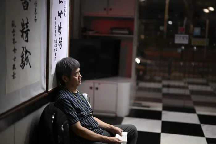 A man sits in a chair with his back against the wall (Stuntman)