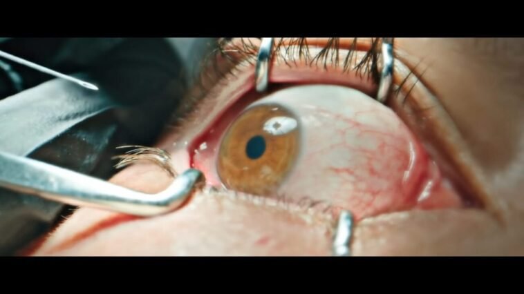 An eye is held open by surgical devices, as a needle is prepared to be inserted.
