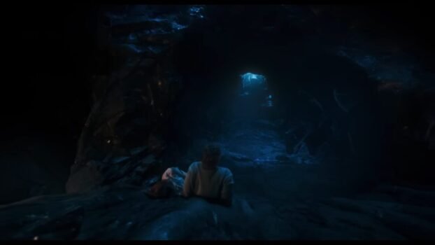 Tim watches the entrance to the cave up above draped in a purplish hue