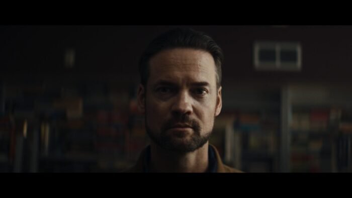 An earnest looking man with a beard looks into the camera