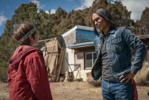 Ghost Eye (Zharn Mclarnon) talks to Cal (Gavin Maddox). Ghost Eye is wearing a blue jacket and blue jeans. Cal is wearing a red hoodie.