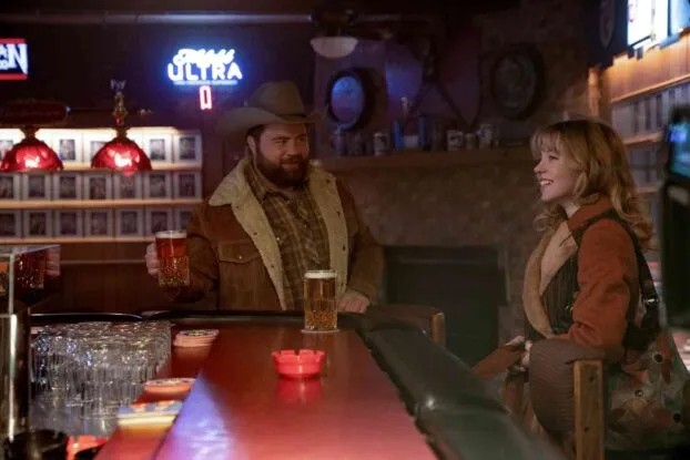 Lefty (Paul Walter Hauser) and Penny Jo (Sydney Sweeney) at a bar. Lefty is bringing a drink to Penny Jo.