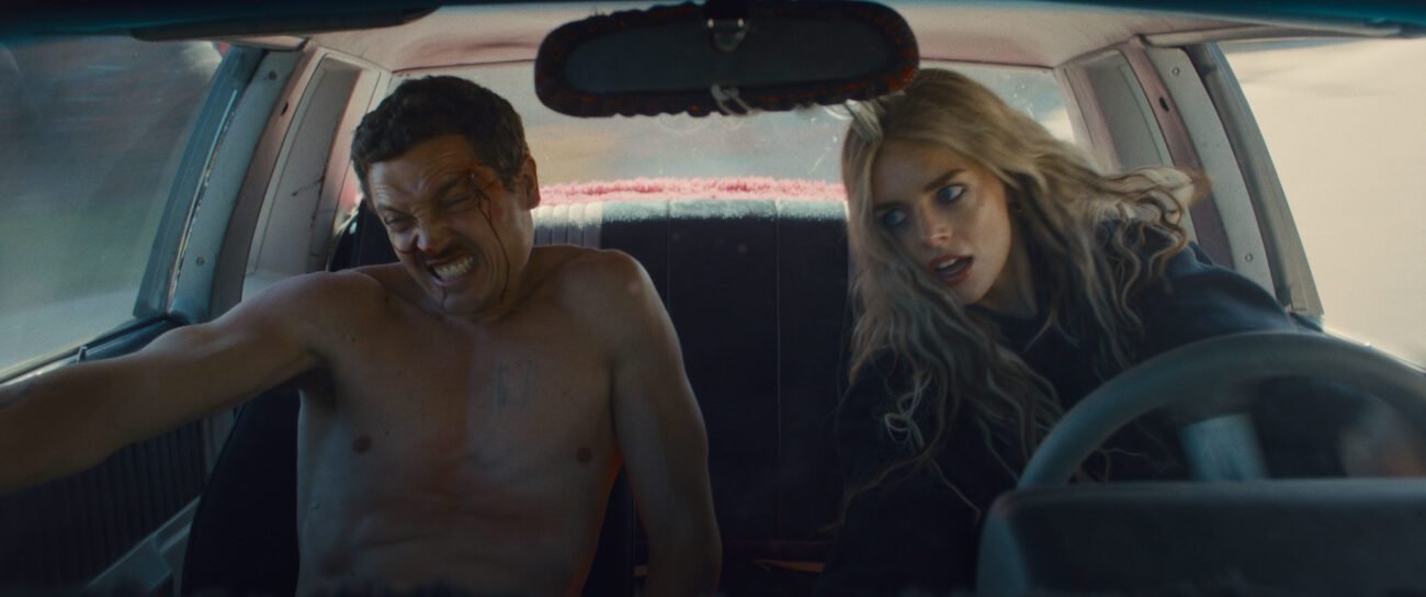 John is seen naked in the passenger seat while Edie is seen driving a car, both are leaning to their right as the car turns. (Eeenie Meanie)