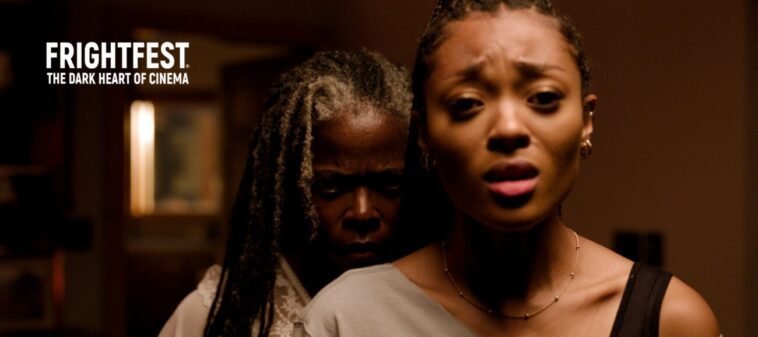 An older woman stands sinisterly close behind a younger woman (Noseeums)