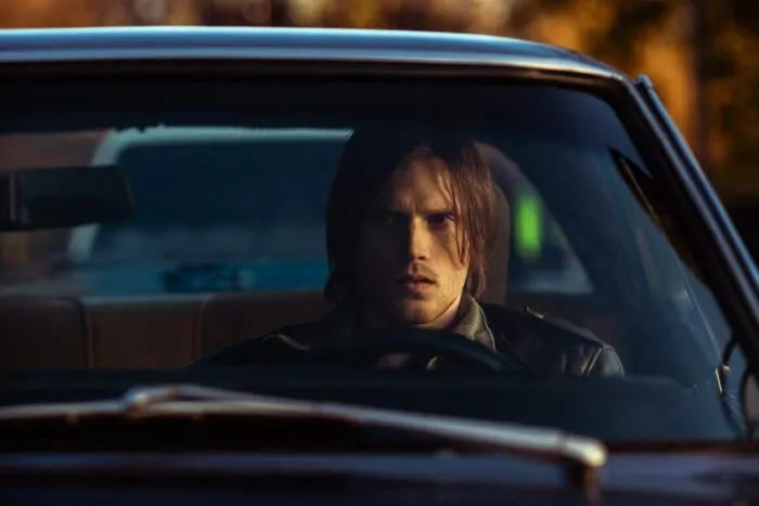A man looks intensely through the windshield of his car.
