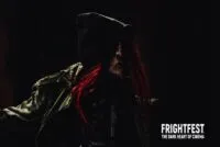 213 Bones' slasher is dressed in a black leather jacket, the mask is seen while some of the red hair peaks through the jacket's hood.