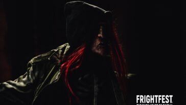 213 Bones' slasher is dressed in a black leather jacket, the mask is seen while some of the red hair peaks through the jacket's hood.